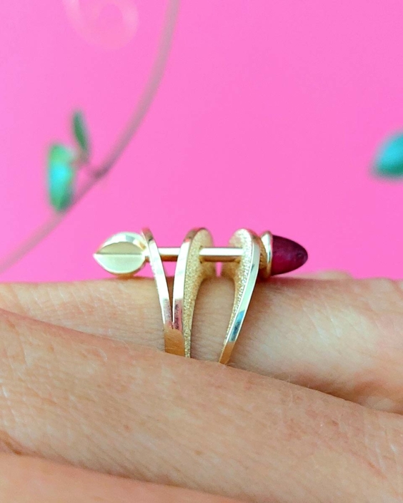 Geelgouden ring Cupido met roze toermalijn Geelgouden ring Cupido met roze toermalijn in een ontwerp van drie vloeiende banden met hierdoor een pijl.